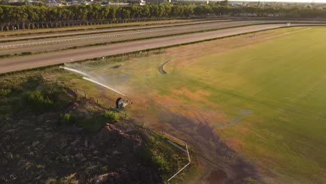 tomada de órbita de un poderoso rociador regando la hierba verde del hipódromo de san isidro, buenos aires, llamarada solar