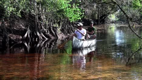 two men row a canoe through the florida everglades