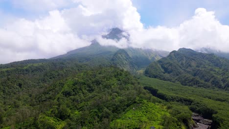 vista aérea de la ladera de la montaña cubierta de bosques y prados que se divide por el valle a medida que la lava fluye cuando un volcán entra en erupción