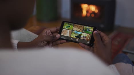 hands of african american woman using smartphone and lying on sofa