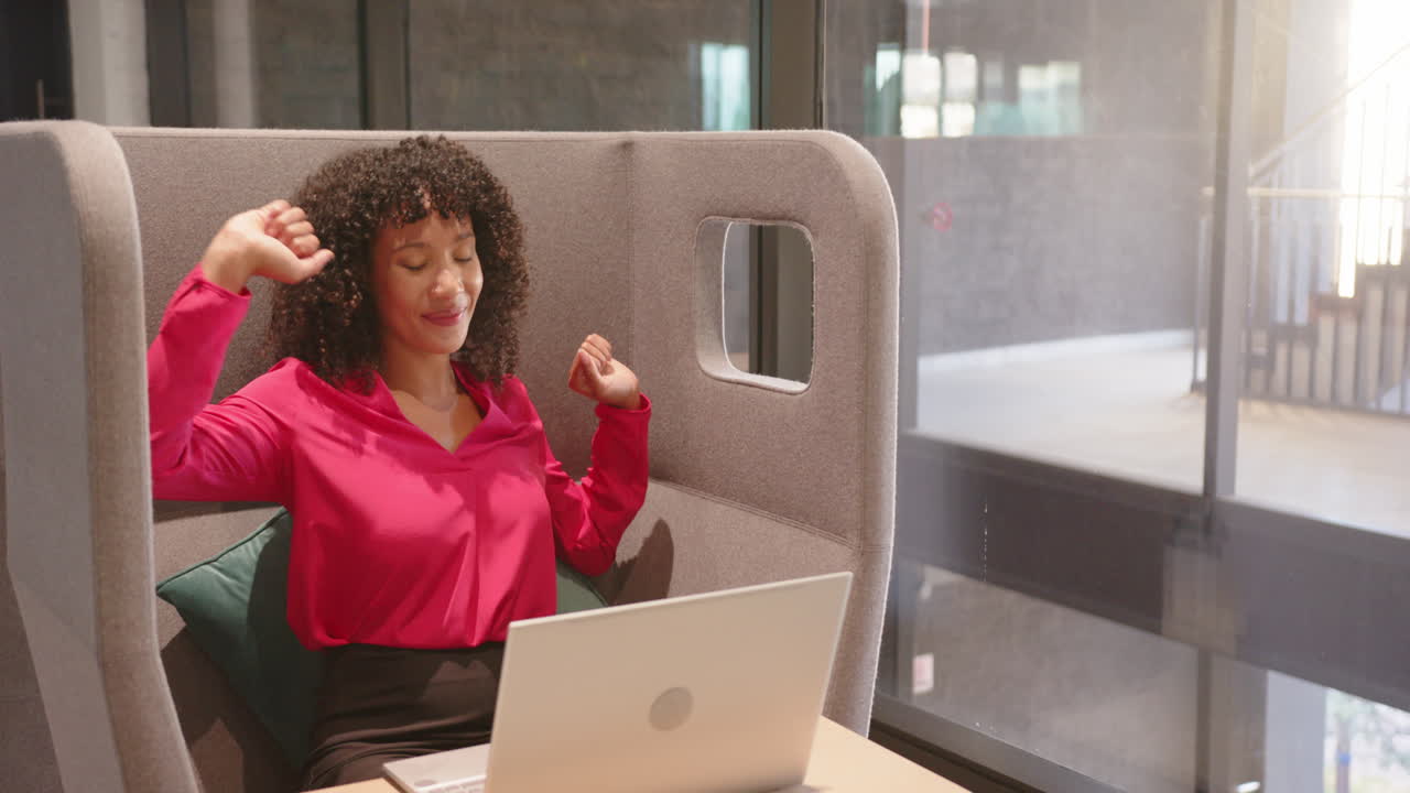Stretching and relaxing, woman taking break from work with laptop in office