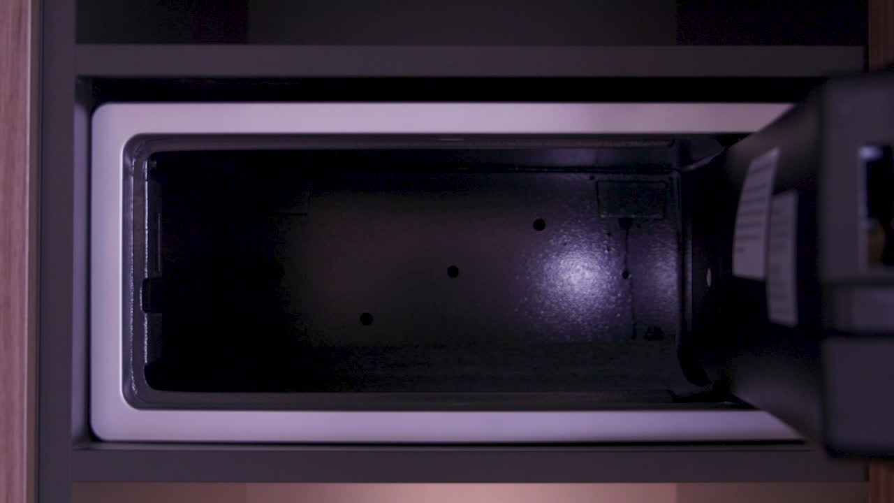 A person opens a hotel safe to retrieve a bottle of beer, demonstrating the ease of accessing items stored securely in hotel accommodations.