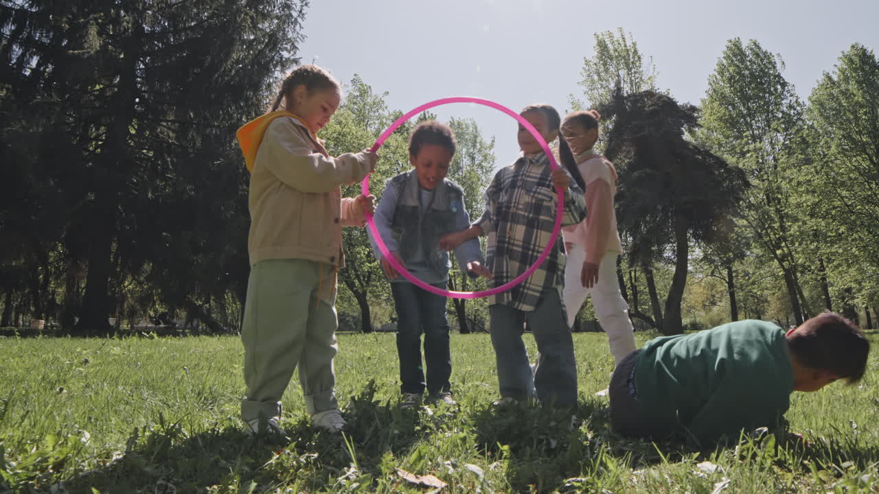 Children playing with a hula hoop in the park