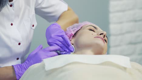 cosmetologist in sterile gloves pricking injections into the neck in beauty clinic. female patient on neckline procedure
