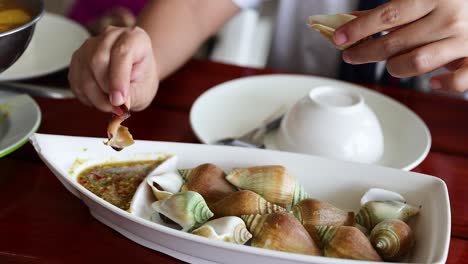 person eating seafood with dipping sauce