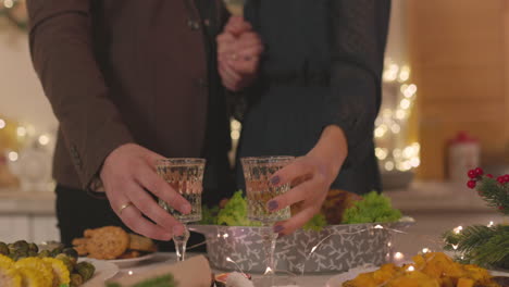 loving couple taking champagne glasses from table and toasting at home on christmas