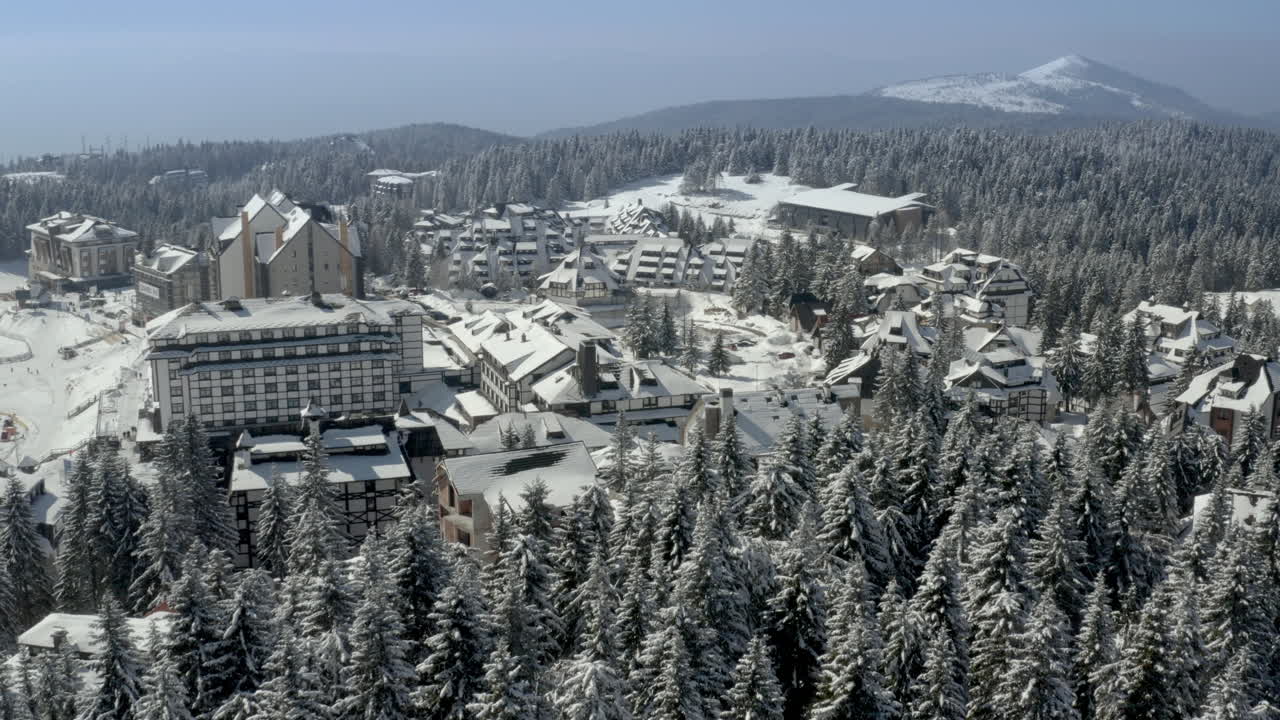 Vista aerea di un resort di montagna innevato con chalet e alberi sempreverdi