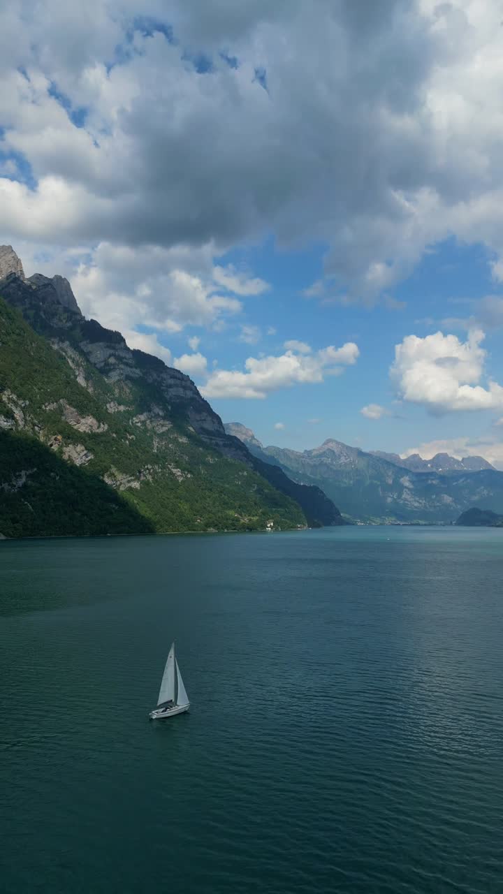 Walensee Swiss alpine region Lake Walen sailing boat surrounded by Churfirsten mountain, vertical video