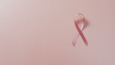 Video-of-pink-breast-cancer-ribbon-on-pale-pink-background