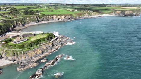 ireland coast aerial establishing shot of a sheltered fishing harbour at boatstrand copper coast waterford on a bright summer day