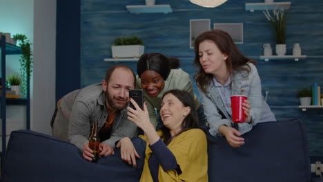 mixed race friends chilling in living room during night party while watching online movie