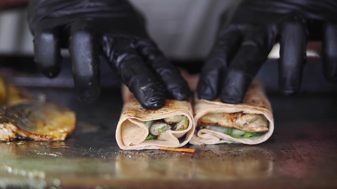 Koch bereitet gegrillte Fisch-Wraps auf heißer Grillplatte zu