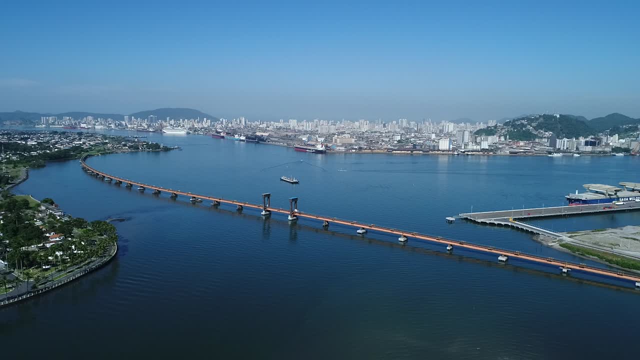 Railway bridge inside the sea in the largest port in latin america, drone filming this immensity of sea and ships with slow movement ahead, intense maritime trade, cargo handling, sunny blue sky day