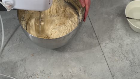 High-angle-view-of-chef-using-hand-mixer-to-mix-cheesecake-filling