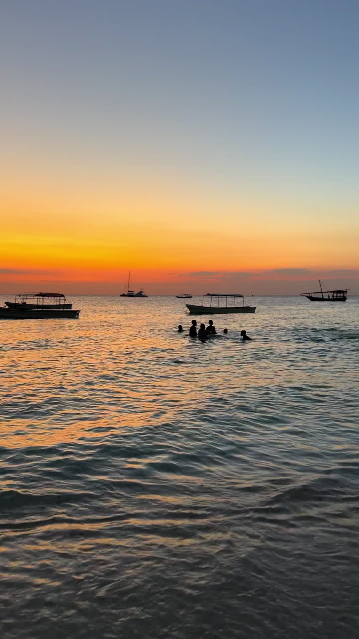 Sunset at the Beach with Boats and People Swimming