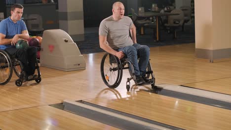 two young disabled men in wheelchairs playing bowling in the club