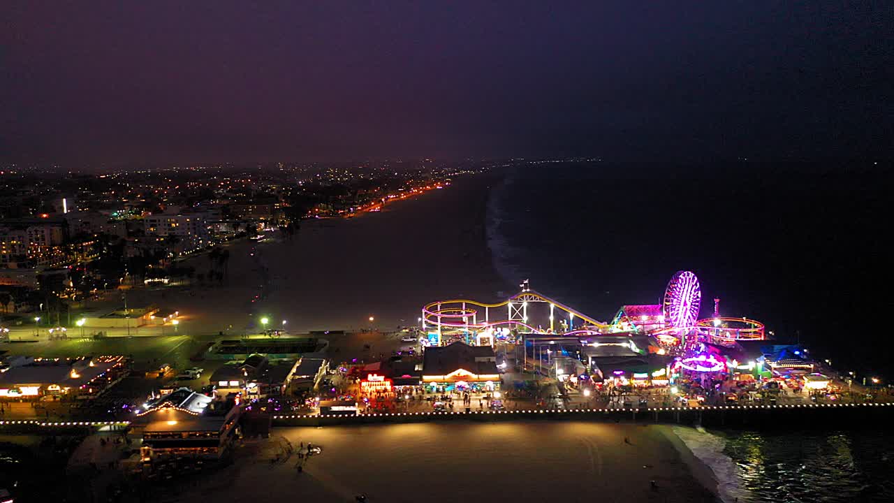 Side aerial drone view of the Ferris wheel and roller coaster at the Santa Monica Pier near Los Angeles California.