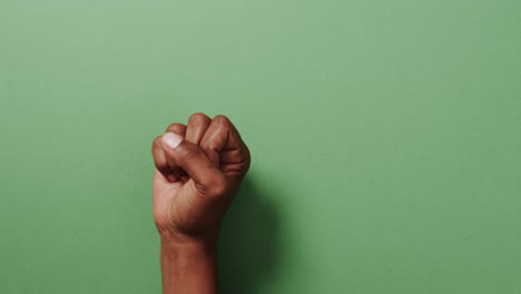 cerca de la mano de un hombre biracial que muestra un signo de paz con espacio de copia en un fondo verde