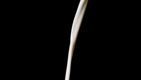 macro shot of pouring milk in slow motion in front of black background