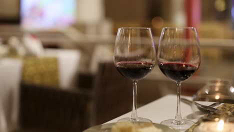 two wine glasses on a table in a dimly lit restaurant, creating a warm and intimate atmosphere