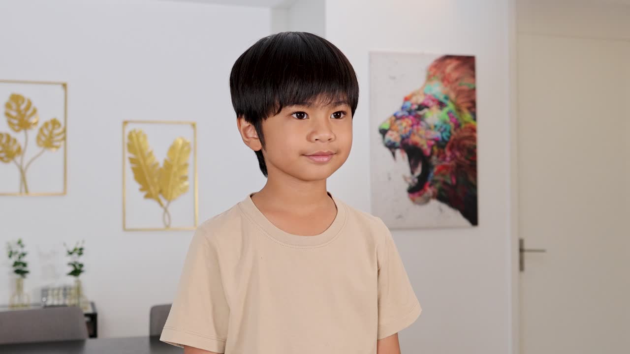 Young boy smiles and gives thumbs up in bright, contemporary room with colorful wall art