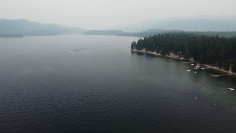 Toma-De-Drones-En-Sentido-Antihorario-De-La-Orilla-Y-El-Agua-En-El-Lago-Payette-En-McCall,-Idaho,-En-Un-Día-De-Verano-Con-Mucho-Humo.