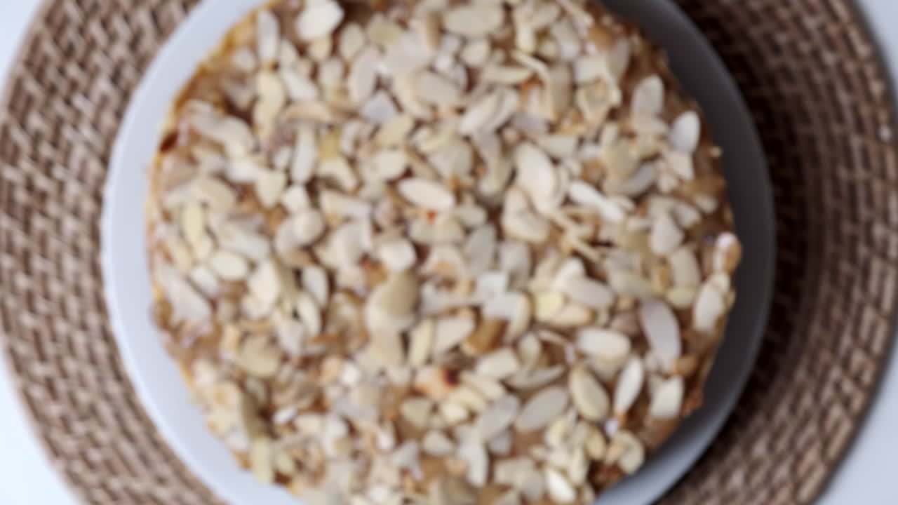 vista superior de tarta de queso saludable con copos de almendras en fondo redondo de ratán