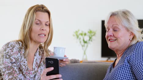 Mother-and-daughter-using-mobile-phone-in-living-room-4k