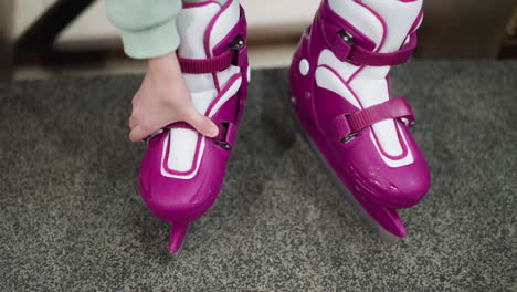 close-up of purple ice skates being fastened by a person, the scene captures the detailed process of preparing ice skates for use