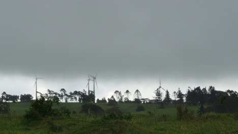 Wind-turbine-in-a-stormy-weather-with-green-farm-land,-wide-static-shot