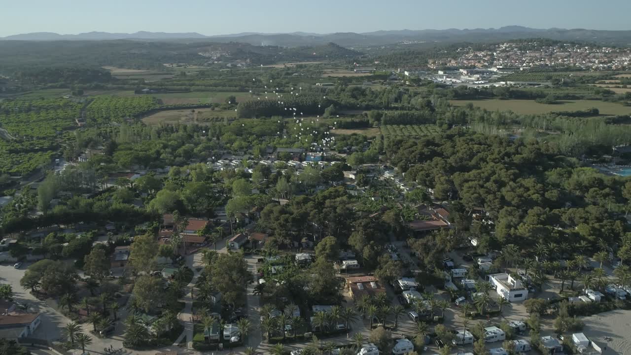 una vista aérea de un grupo de globos lanzados que vuelan por el cielo sobre una ciudad costera en un día soleado