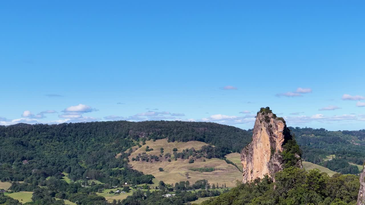 Panoramic view of Nimbin Rocks under clear blue skies, showcasing natural rock formations and lush greenery