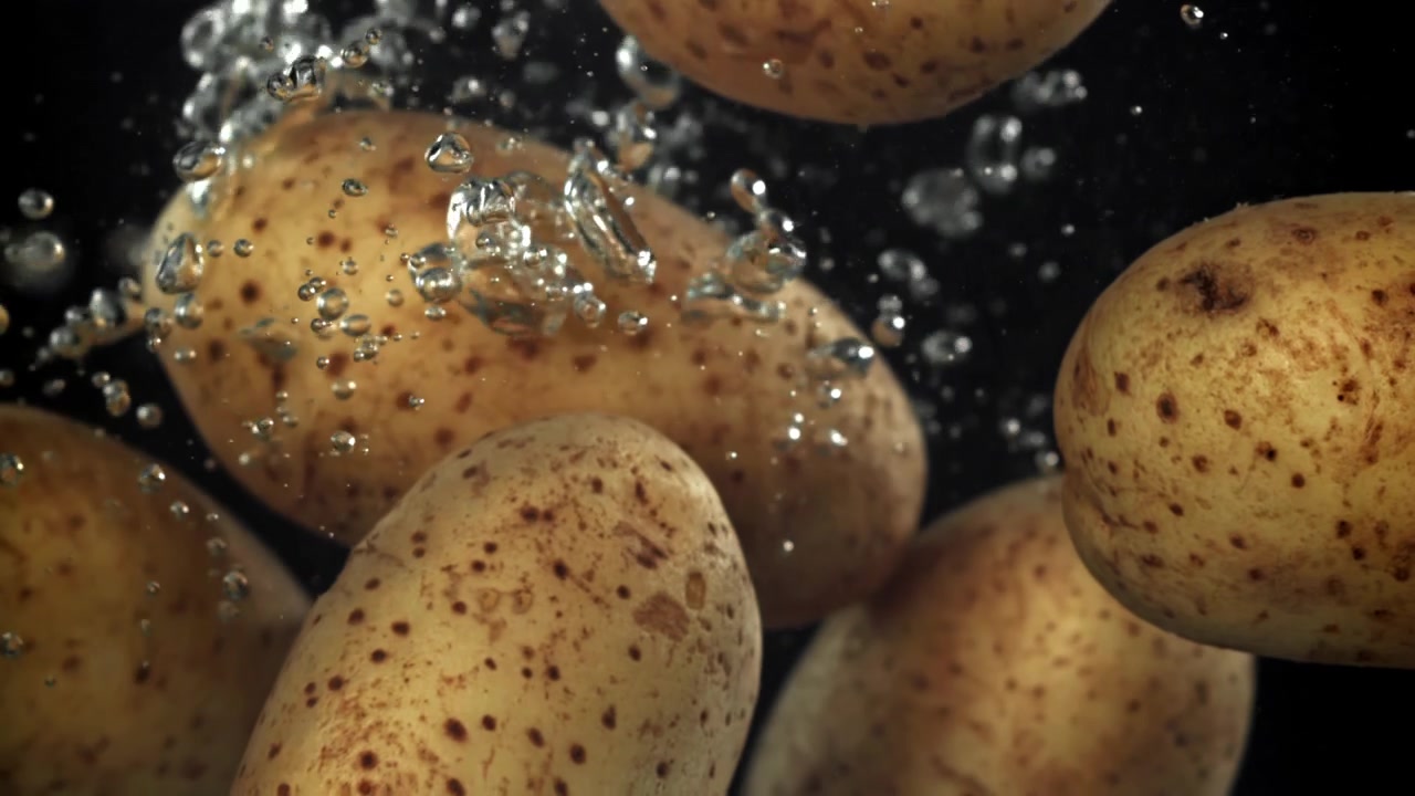 Patate fresche che cadono nell'acqua con bolle al rallentatore