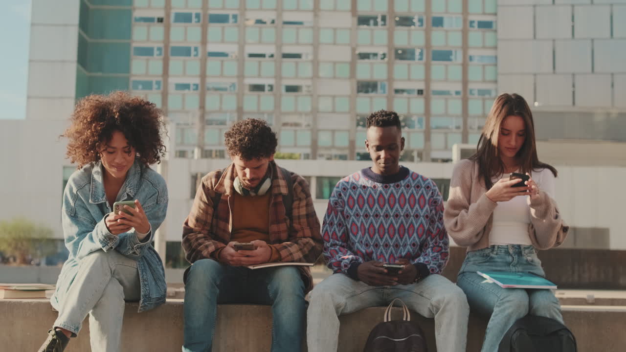 Gruppo di studenti universitari che usano i telefoni all'aperto