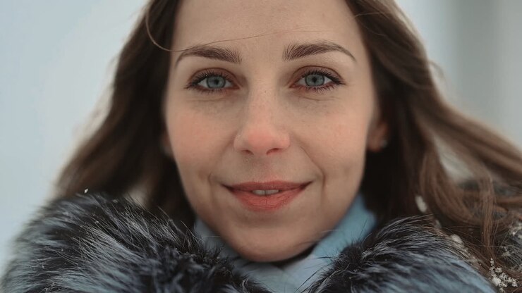 Primer plano de mujer mirando a cámara, posando con ropa de invierno y sonriendo
