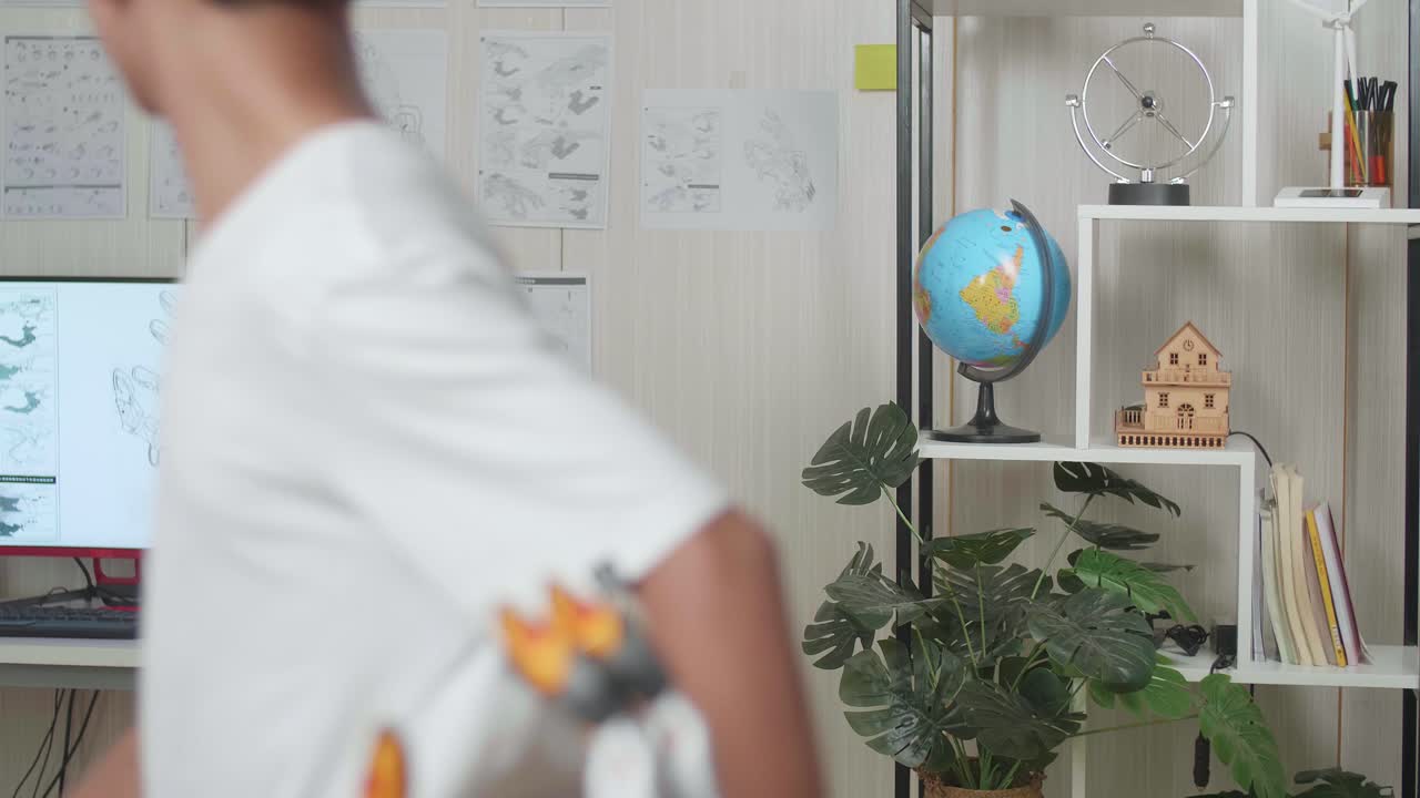 primer plano de un niño asiático caminando para mirar las imágenes en la pared mientras trabajaba sobre una mano de cyborg en casa