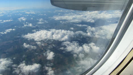 through airplane window view, aircraft window, sky, clouds, up in the sky during flight, looking through the window seat, inside cabin, aerial cloudscape view