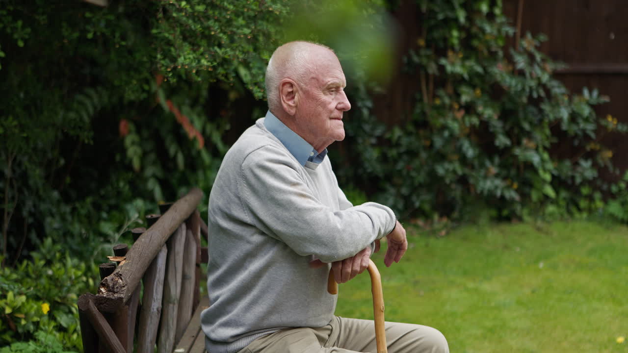Elderly man sitting on a bench in a garden