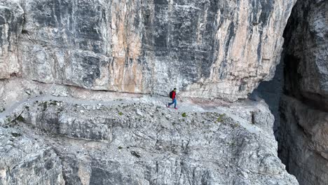 a mountaineer walking along an exposed hiking trail in the dolomites in italy