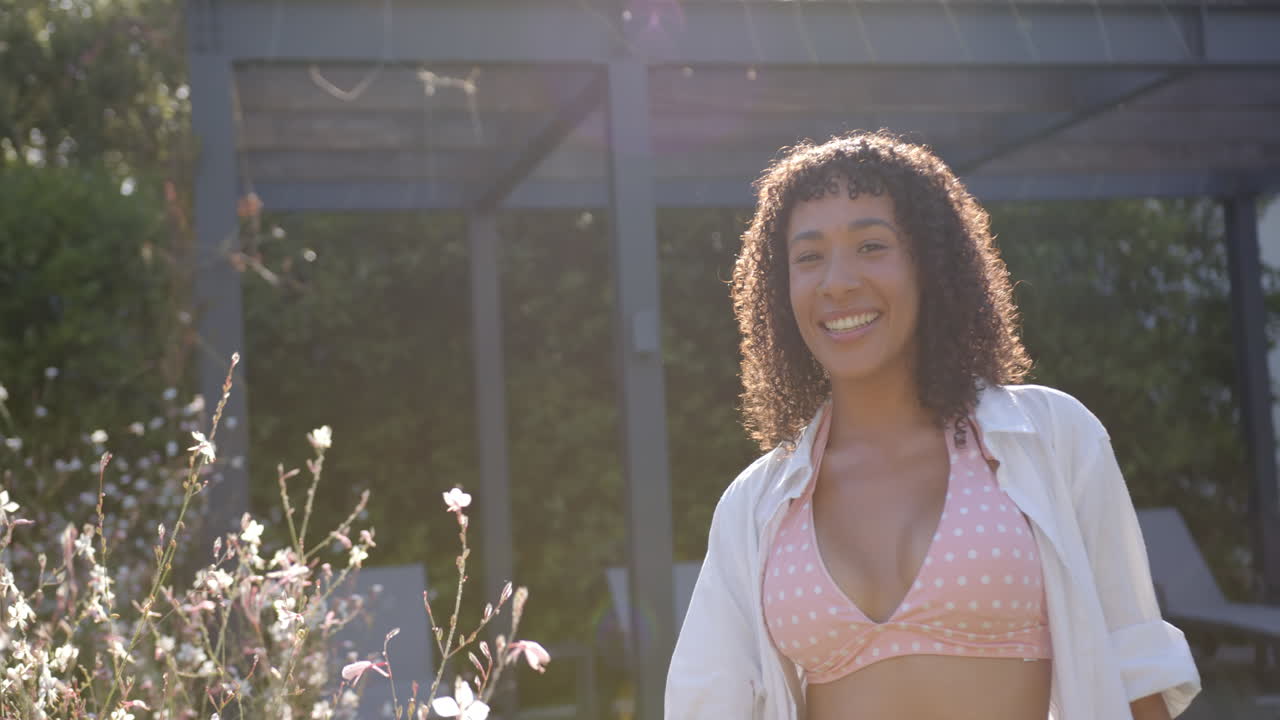 Smiling woman in polka dot bikini top enjoying sunny day by poolside, copy space