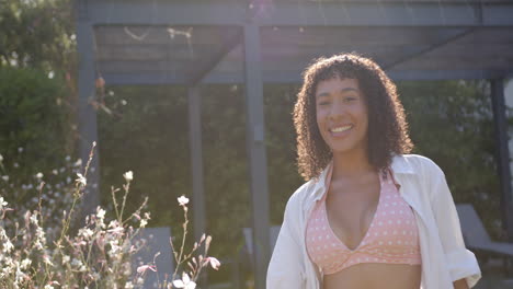 Smiling woman in polka dot bikini top enjoying sunny day by poolside, copy space