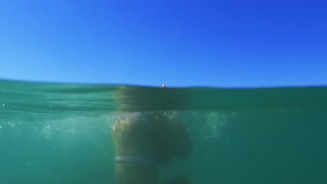 half underwater scene of young redhead girl rolling back in sea water with horizon in background