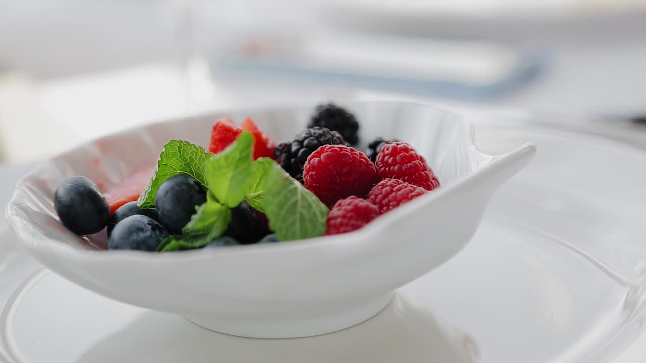 소녀는 손으로 접시에서 베리를 꺼낸다. 여자 손의 클로즈업