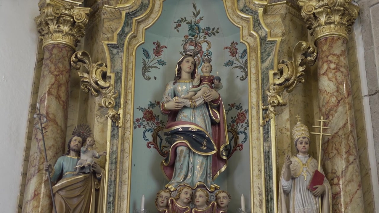 Bohatě zdobený kostelní oltář se sochou Panny Marie držící Ježíška.