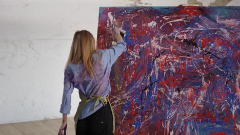 woman drawing abstact picture using spraying paints in art studio