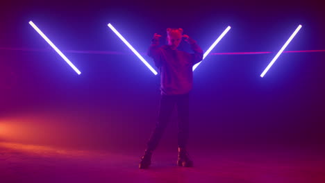 cool woman wearing hood preparing dance performance on night club stage.