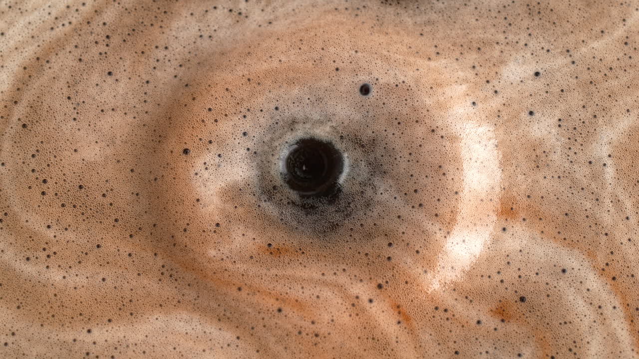 gotas de café goteando al líquido espumado negro haciendo un salpico y ondas en macro y cámara lenta