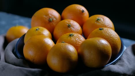 pile of unpeeled round ripe orange mandarin in a plate