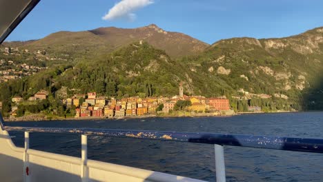 Vista-Desde-El-Barco-De-Crucero-Turístico-Del-Pueblo-Italiano-De-Varenna-Iluminado-Por-La-Luz-Del-Atardecer