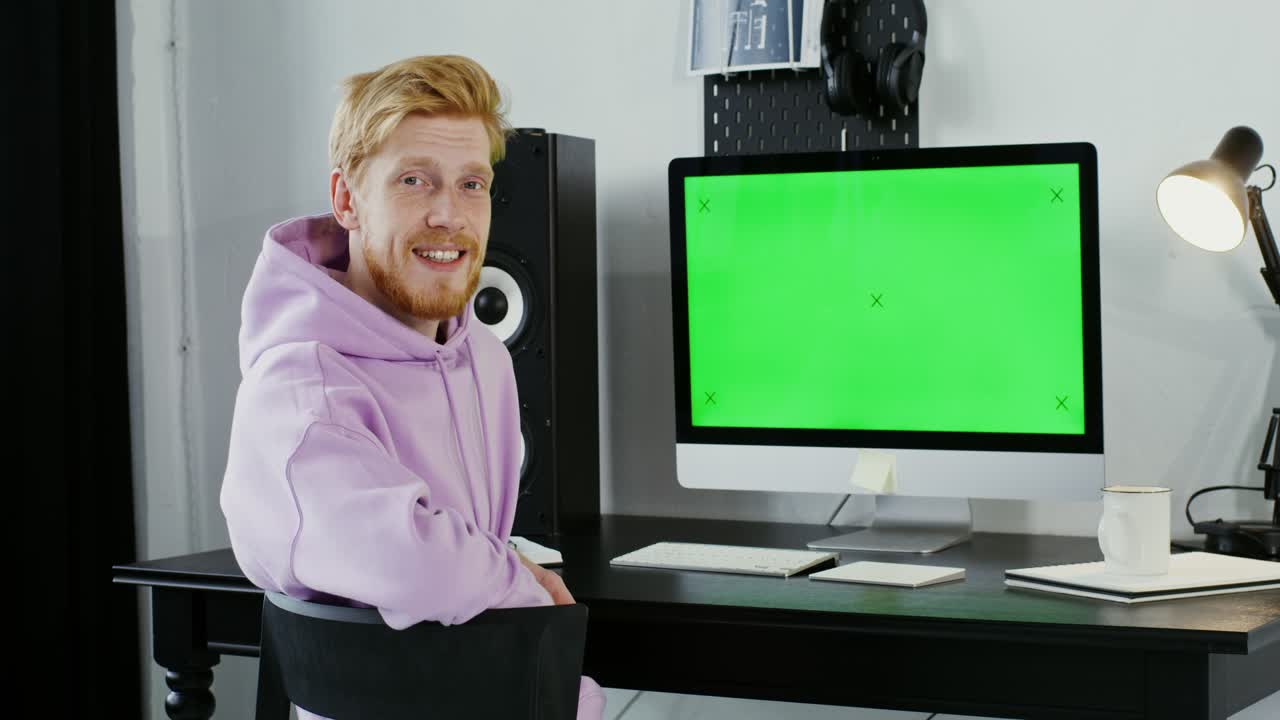 Man working at a home office with a green screen computer